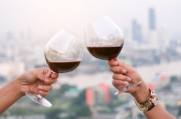 Hand of a lover's dinner is celebrated with red wine at a restaurant in a romantic atmosphere. Sunset and modern city background