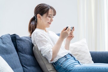 家で携帯を触るアジア人女性

