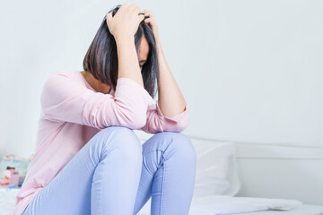Fototapeta premium Upset depressed young woman sitting on bed feeling strong headache migraine, sad tired drowsy teenager exhausted girl resting trying to sleep after nervous tension and stress, somnolence concept