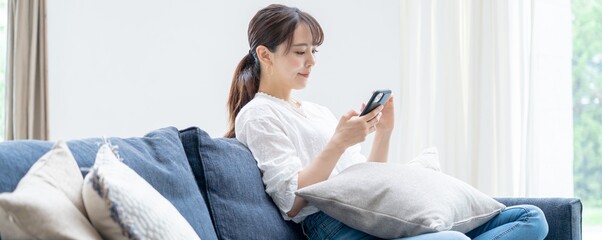 家で携帯を触るアジア人女性 