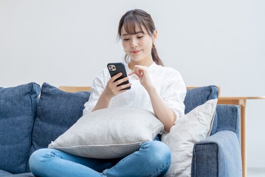 家で携帯を触るアジア人女性
