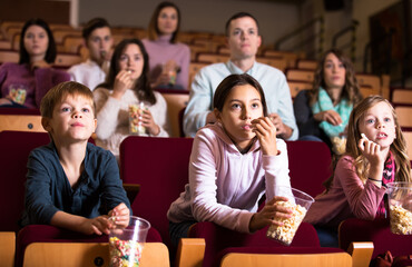 Group of people eating popcorn during film in cinema