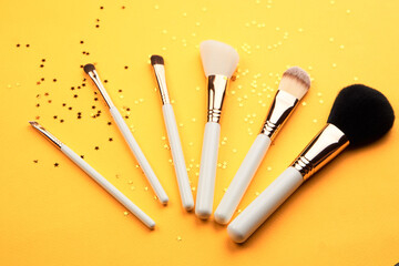 Makeup brushes with sparkles on a yellow background professional cosmetics