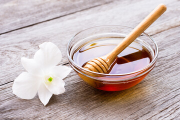 Honey in wooden bowl with honeycomb on wood table background.