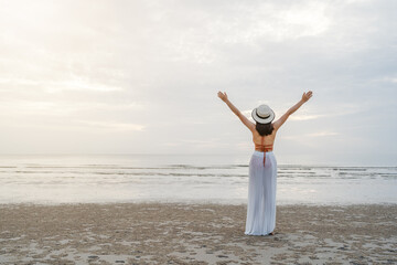 Fototapeta na wymiar freedom woman in bikini walking with arms raised on sea beach