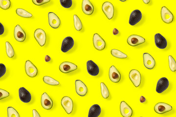 Avocado. Background made from isolated Avocado pieces on yellow background. Flat lay of fresh ripe avocados and avacado pieces.