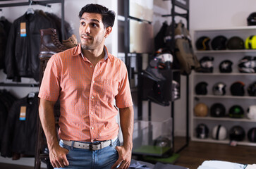 Fototapeta na wymiar Adult positive european man is posing near modern equipment for motorbike in the store.