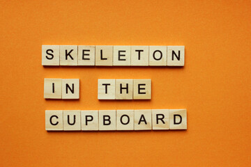 Words Skeleton in the Cupboard. Wooden blocks with an inscription on an orange background. Bulletin board. The concept of the holiday is Halloween. The view from the top. Copy space