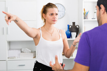 Fototapeta na wymiar Irritated young woman emotionally gesturing in quarrel with man