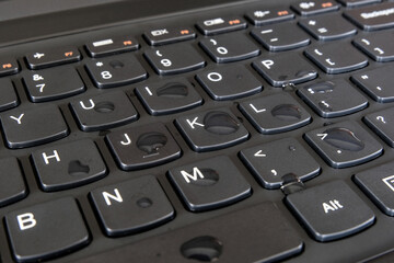 Water droplets on a computer keyboard surface left behind after being used by wet hands or sweaty...