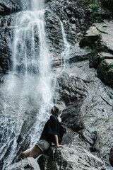 young woman on the background of a mountain waterfall with a ponytail 