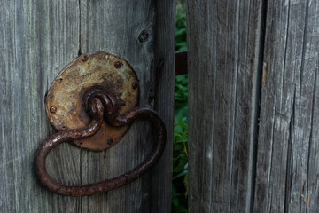 old rusty handle in the form of a ring on the grey gate