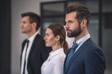 Bearded male and his female and male collegues standing half turned