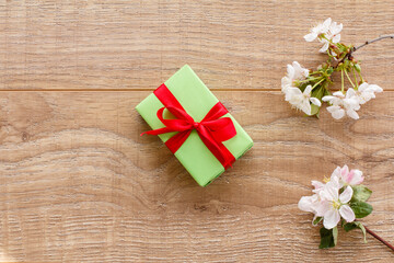 Fototapeta premium Gift box with cherry flowers on the wooden background.