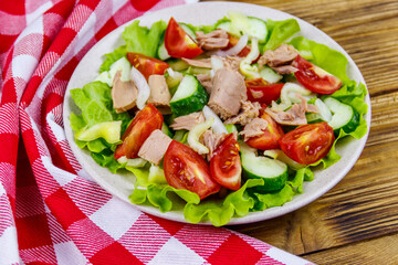 Tasty tuna salad with lettuce and fresh vegetables on wooden table