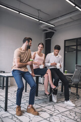 Female and two male colleagues sitting on table, having lunch