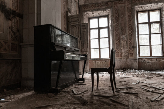 Old broken piano and chair in abandoned ruined mansion. Haunted house interior concept.