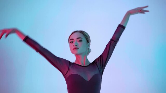 Graceful ballerina performing classical ballet moves on blue and pink background