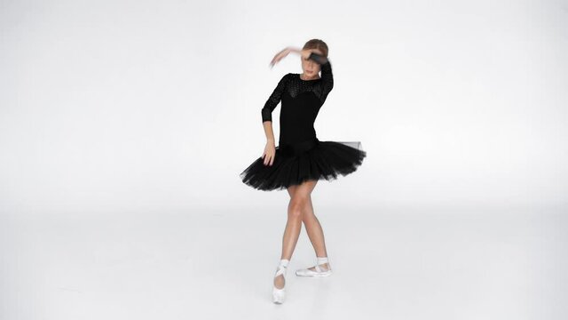 Elegant ballerina in tutu dancing and looking at camera on white background