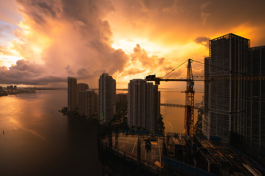 Aerial view of sunrise over Brickell key and port of miami taken in downtown with skyscraper construction site in foreground 