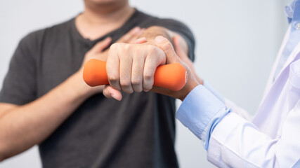 physiotherapist doctor rehabilitation consulting physiotherapy giving dumbbell exercising treatment with patient in physio clinic or hospital.