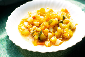 Mix of stewed vegetables on a white plate in cafe. Vegetable stew in tomato sauce. Cooked vegan or vegetarian food.