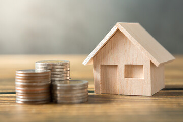 Model house, coins stack on wooden desks and loft walls with sunlight and copy space  for money saving concept