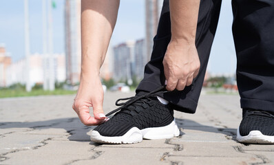 woman fastening shoe-laces on her trainers the sports ground