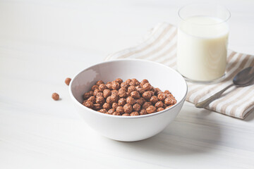 Chocolate balls corn flakes in white bowl, white background. Breakfast food concept.