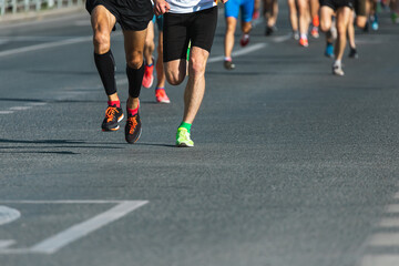 A close-up of the legs of the running track and field athletes on the asphalt. Marathon runners in special sneakers