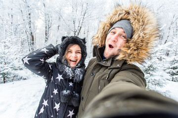 Season and relationship concept - Funny couple taking selfie in the winter time