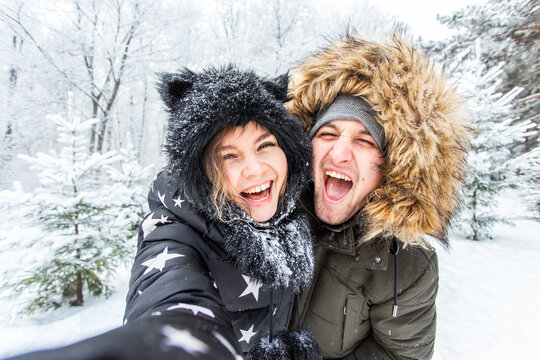 Season, love, technology and leisure concept - happy couple taking selfie by smartphone over winter background