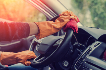 female hand cleaning her car interior from coronavirus and pandemic with disinfectant fluid