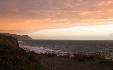 Fototapeta premium Beautiful seascape view. Sunset sky with sea, pastel colors. Mountains landscape and seacoast. High view to ocean coast waves. Soft focus