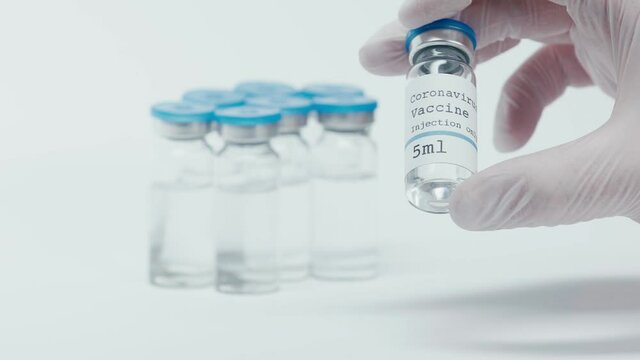 coronavirus vaccine lettering on bottle in hand of scientist on white