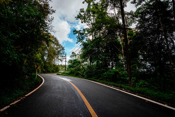 Fototapeta na wymiar Countryside road passing through the serene lush greenery and foliage tropical rain forest mountain landscape on the Doi Phuka Mountain reserved national park the northern Thailand