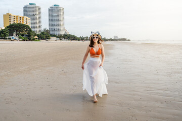 Fototapeta na wymiar cheerful woman in bikini walking on sea beach