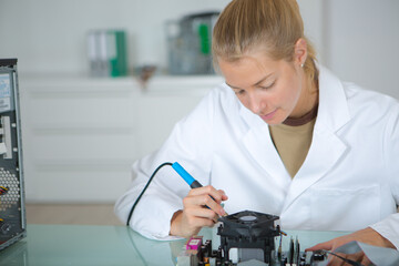 young woman solders and adjusts electronic device