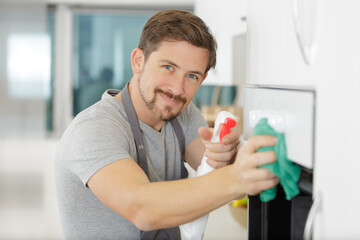 man wiping an oven