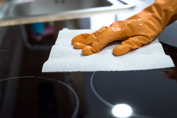 Female hand cleaning modern glass ceramic electric surface with a sponge in her kitchen