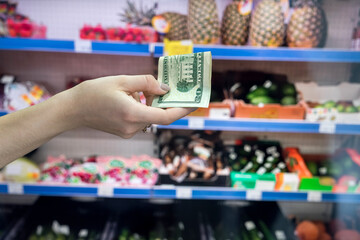 man holds dollars in the supermarket