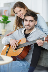 couple sitting on the sofa while young man plays guitar