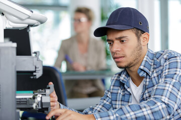 young male technician is repairing a printer in an office
