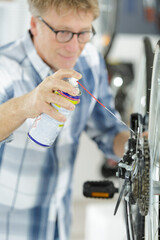 mature bike mechanic oiling a bike