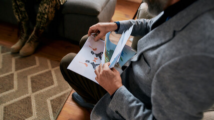 Mature psychologist choosing picture with ink stain, Rorschach Inkblot during therapy session with military man. Soldier suffering from depression, psychological trauma. PTSD concept