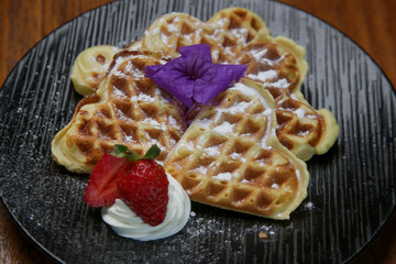 Belgian waffles served with ice cream decorated with edible flower	
