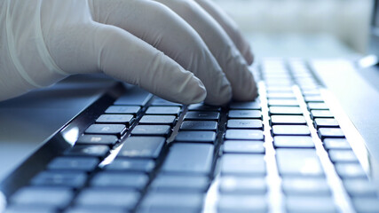 Closeup Image with Hands Wearing Protective Gloves Using the Laptop Keypad