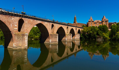 Fototapeta na wymiar Montauban city on sunny day. Medieval bridge over the Tarn river. France