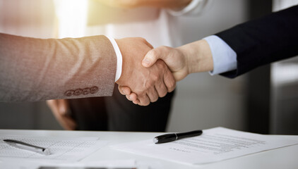 Business people shaking hands finishing contract signing in sunny office, close-up. Handshake and marketing