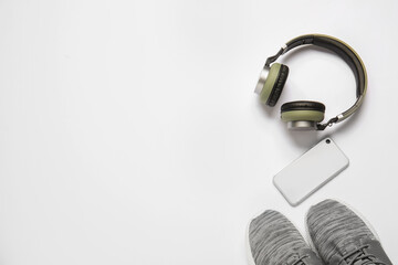 Sportive shoes, headphones and mobile phone on white background